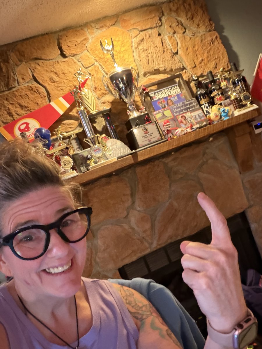 Tish pointing at her mantle of pool trophies